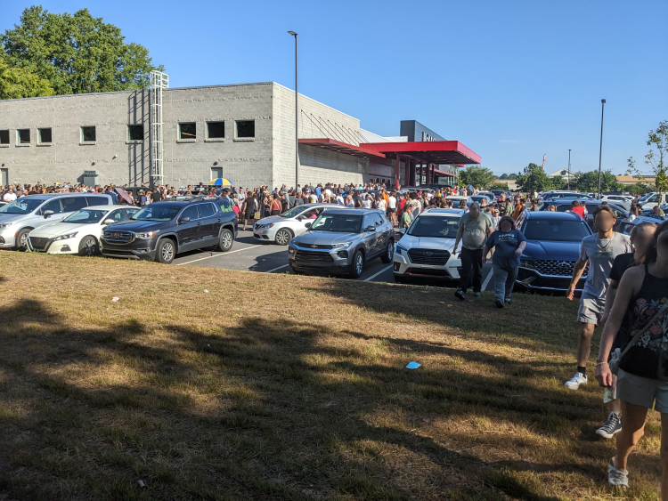 Photo looking across the full parking lot at McKay's Mebane. Each space is occupied with a vehicle and a line of people winds through the lot.